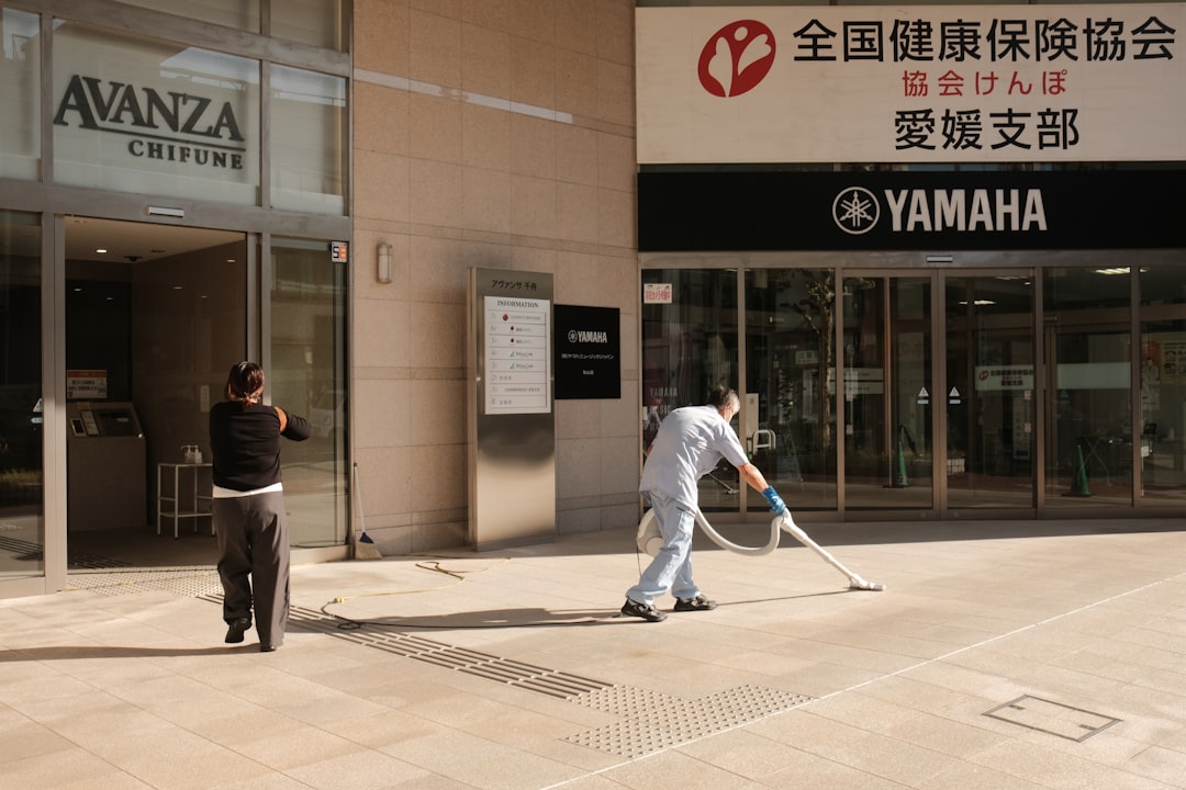 two-people-cleaning-outside-a-building-entrance-bgimfj7i6ec